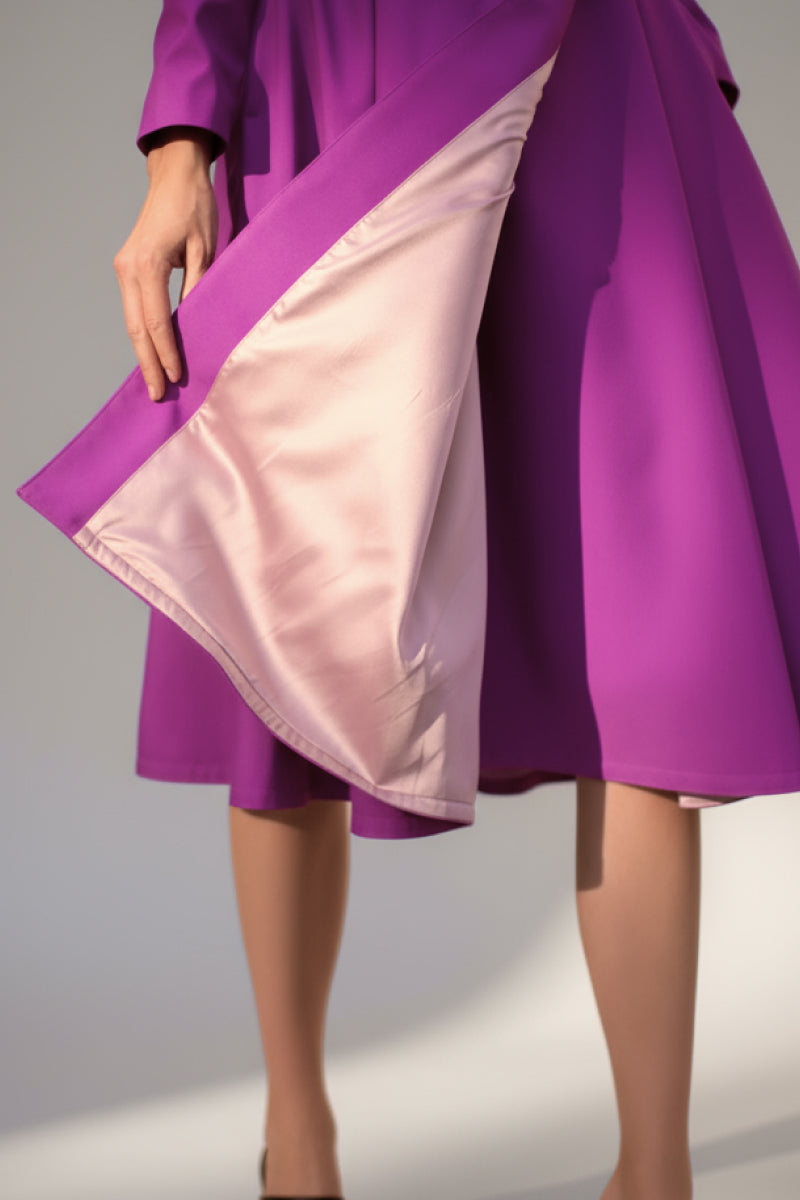 A person wearing the looselyboho Water-Repellent Rain & Shine A-Line Hooded Raincoat in purple holds out the skirt to reveal its light pink lining. The cropped image focuses on the lower half, highlighting graceful lines and fabric details.