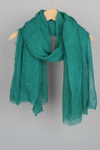 A teal, textured all-weather Color-POP Scarf by looselyboho is hanging on a wooden hanger against a plain gray background. The scarf has frayed edges, providing a casual and slightly rustic look.