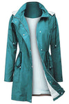 A long teal waterproof raincoat is displayed against a plain background. It features a broad collar, adjustable waist ties, snap buttons, and a full front zipper. The inside lining is white with vertical gray stripes, visible as the coat's front is partially open. The displayed product is the STRIPED TURQUOISE OASIS WINDBREAKER JACKET by looselyboho.