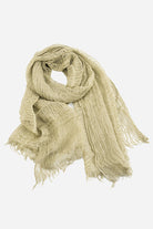 A light beige, loosely woven scarf with frayed edges, made from ultra-breathable linen, is displayed against a white background. The Lightweight Linen Scarf from looselyboho appears soft and lightweight, exuding artisanal charm and suitable for casual wear.