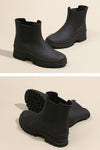 Two images of black ankle-length Non-Slip Rain Boots by looselyboho with SuperGrip Soles and a rugged tread pattern. The first image shows the waterproof boots standing upright side by side. The second image displays one boot standing and the other lying on its side, highlighting the detailed sole design.