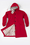 A red "Water Resistant Oversized Hooded Windbreaker Rain Jacket" from The WJacket is displayed on a white background. The coat exudes timeless style with long sleeves and elasticized cuffs, a front button closure, and two large pockets. Its versatility is highlighted by an interior lining adorned with rare beautiful colors in a small red and green floral pattern.