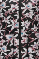 Close-up image of a polyester FLORALSHIFT COAT: THE REVERSIBLE RAINCOAT by looselyboho with a floral-patterned fabric. The design features pink and white flowers with blue centers on a black background. A black zipper and black drawstrings are visible in the center, along with deep pockets that add both functionality and style.