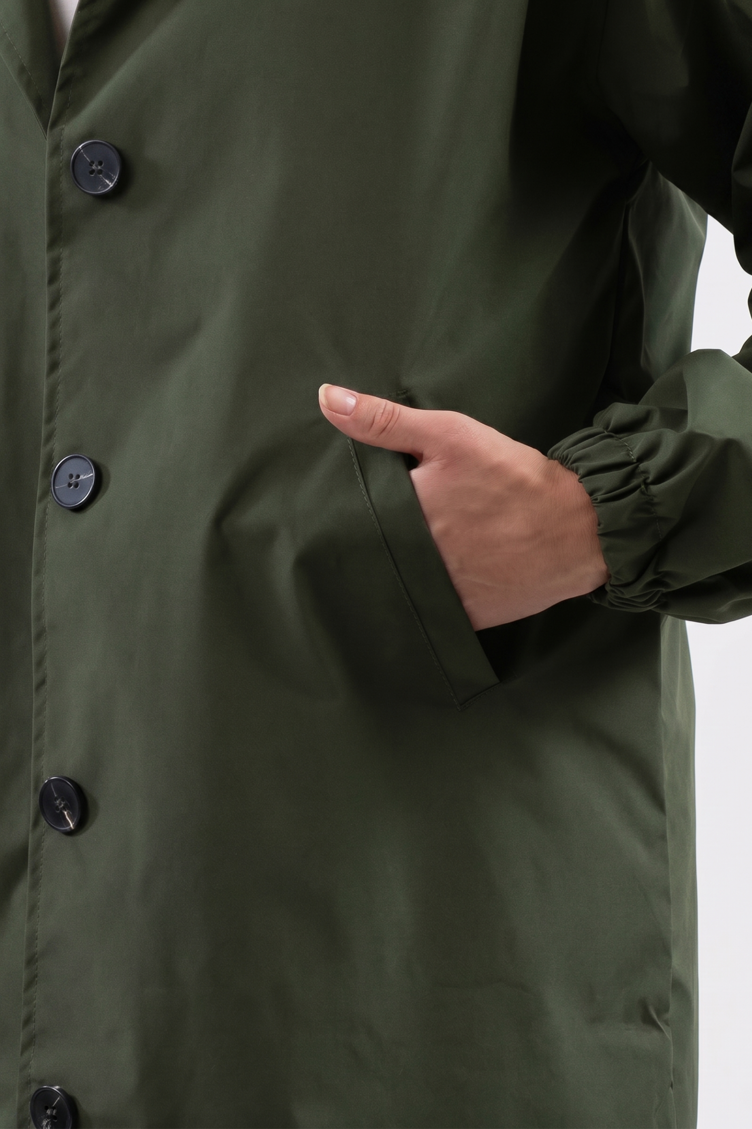A person wearing the Icon Windbreaker Rain Jacket in green places their right hand in the coat pocket. Only their torso and arm are visible against a plain background.