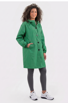 A person with curly hair wears the Icon Windbreaker Rain Jacket in green, paired with gray leggings and white sneakers, standing against a plain light background with one hand in their pocket.