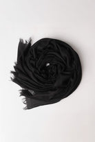 The looselyboho Noir Eclipse 100% Cashmere Scarf, featuring frayed edges, is styled in a circular shape on a simple white background.