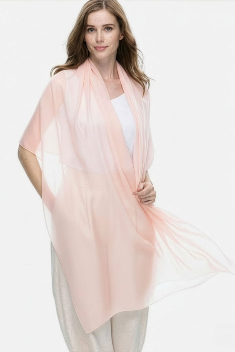 A woman with long light brown hair models the looselyboho Blush Rose 100% Cashmere Scarf over a white top and light pants, standing against a plain white background.