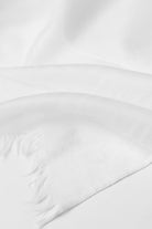 A close-up of the looselyboho Ivory Whisper 100% Cashmere Scarf, featuring a smooth, minimalist texture and soft fringed edges, elegantly laid flat with gentle folds to showcase luxurious simplicity.