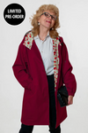 A person in a looselyboho BURGUNDY BLOSSOM WINDBREAKER with floral lining and black pants stands against a plain background. This water-resistant coat is part of a limited pre-order collection, noted by the label in the top left corner.